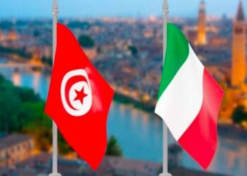 La photo montre l’espace du service des visas de l’Ambassade d’Italie à Tunis. Des demandeurs attendent leur tour devant les guichets. Des agents administratifs traitent les dossiers. Cette scène illustre les démarches habituelles pour obtenir un visa, qui seront temporairement interrompues pendant la période de suspension technique du système informatique.